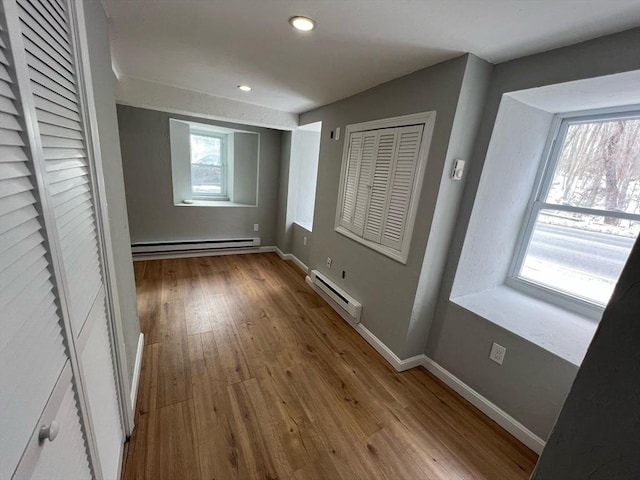 unfurnished bedroom featuring light wood-type flooring, a baseboard radiator, baseboards, and recessed lighting