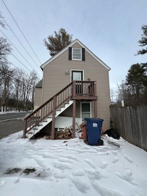 snow covered property featuring stairs and fence