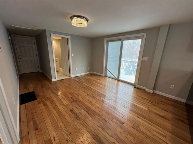 unfurnished bedroom featuring light wood-style floors, attic access, baseboards, and access to outside