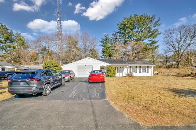 view of front of property with driveway, a front yard, an attached garage, and roof mounted solar panels