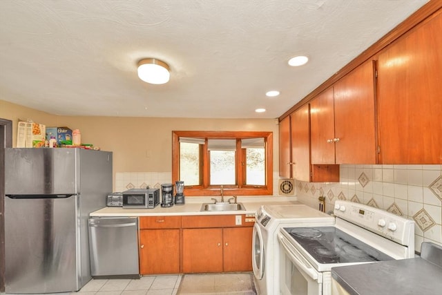 kitchen with stainless steel appliances, a sink, washer / dryer, recessed lighting, and tasteful backsplash