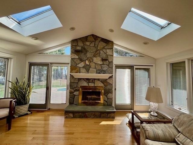 interior space featuring vaulted ceiling with skylight, a fireplace, and wood finished floors