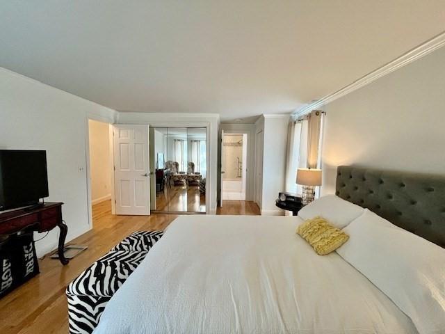 bedroom featuring ensuite bath and wood finished floors