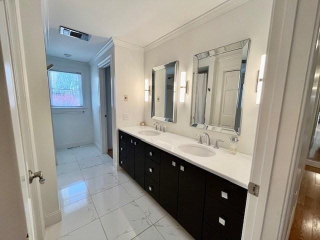 bathroom featuring crown molding, a sink, double vanity, and visible vents