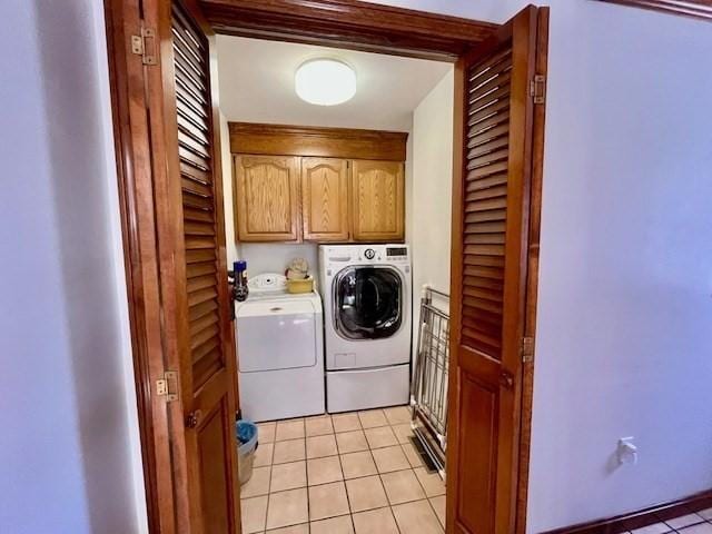 washroom featuring independent washer and dryer, light tile patterned floors, and cabinet space
