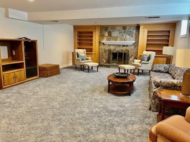 carpeted living area with visible vents, baseboards, built in shelves, and a fireplace