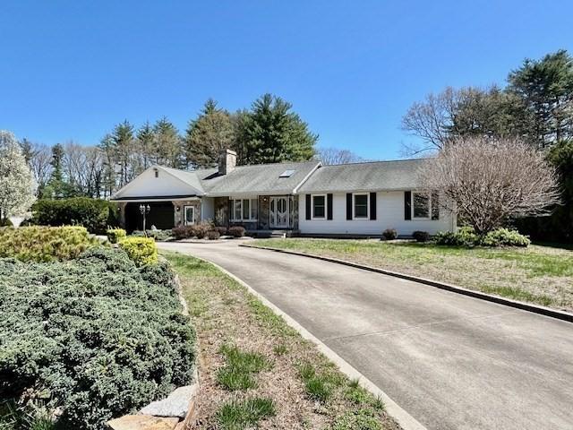 ranch-style house with a chimney, driveway, and a front yard