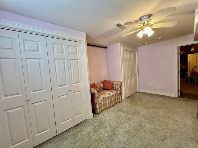 living area featuring carpet floors, ceiling fan, visible vents, and baseboards