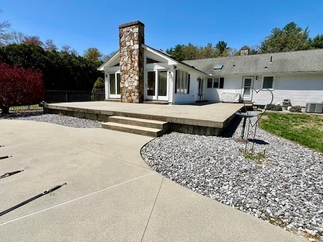 back of property with central air condition unit, fence, a patio, and a chimney