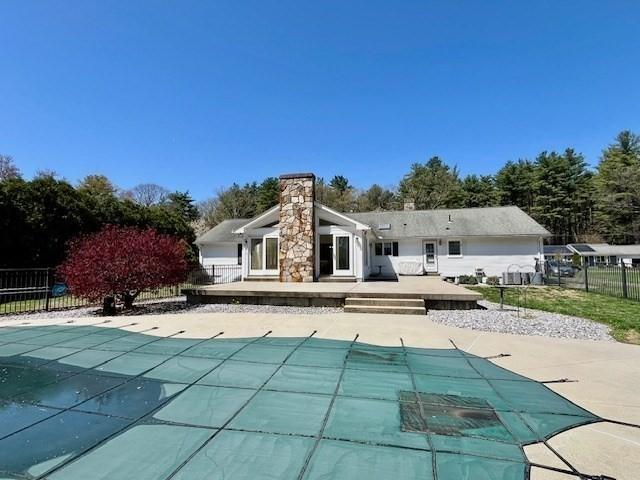 back of property featuring fence, a fenced in pool, a chimney, and a deck