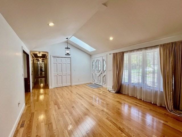 bonus room with baseboards, light wood finished floors, vaulted ceiling with skylight, and visible vents
