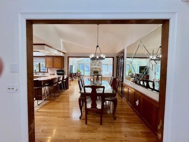 dining space featuring a notable chandelier, lofted ceiling, and light wood-type flooring