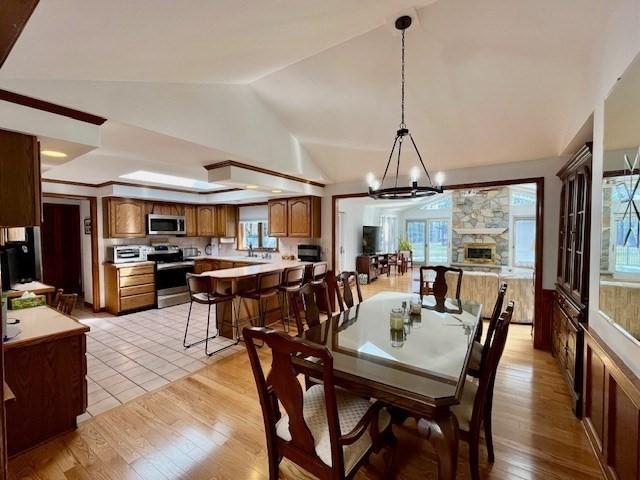 dining area with an inviting chandelier, plenty of natural light, lofted ceiling, and light wood-type flooring
