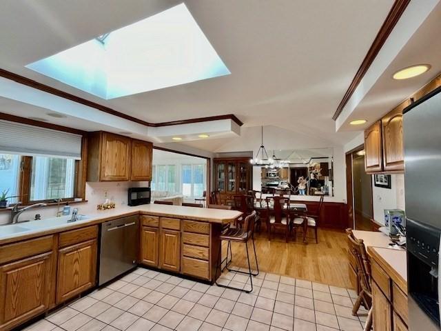 kitchen featuring a peninsula, a healthy amount of sunlight, light countertops, brown cabinets, and stainless steel appliances