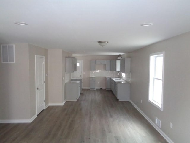 kitchen with sink, backsplash, dark wood-type flooring, and gray cabinets