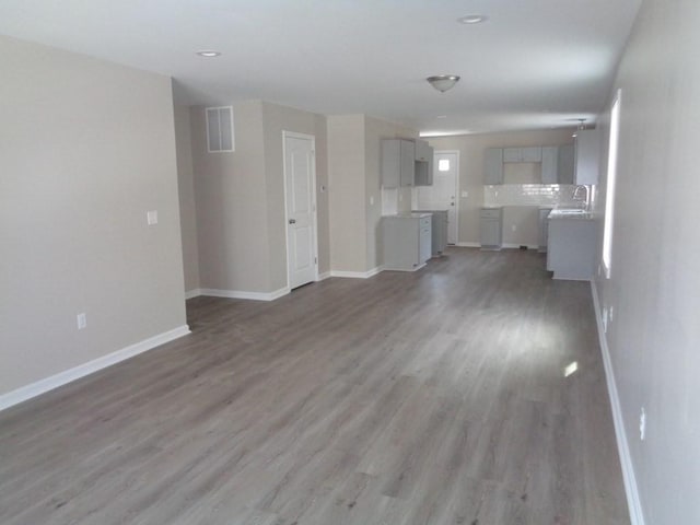 unfurnished living room with hardwood / wood-style flooring and sink