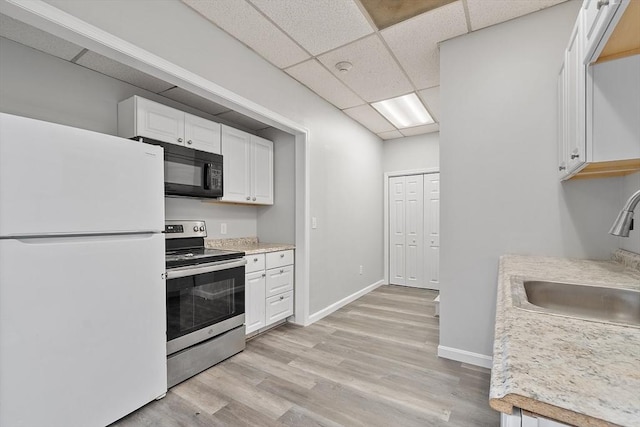 104 Pleasant St, Worcester, MA 01609 - kitchen with freestanding refrigerator, electric stove, black microwave, white cabinets, and light wood-style floors
