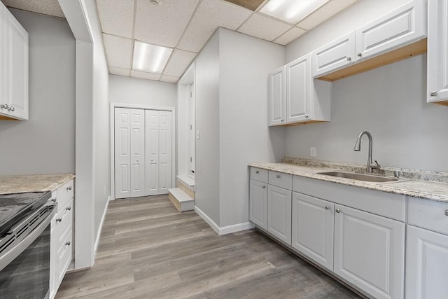 104 Pleasant St, Worcester, MA 01609 - kitchen with electric stove, a paneled ceiling, light wood-style flooring, white cabinetry, and light stone counters