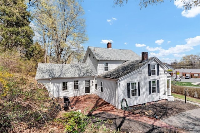 view of property exterior with roof with shingles and a chimney