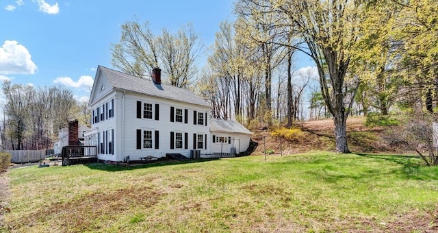 exterior space with a chimney, a yard, roof with shingles, and a deck