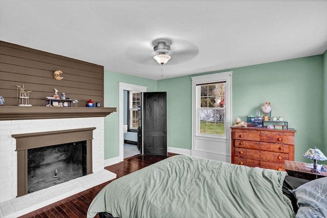 bedroom with baseboards, a brick fireplace, a ceiling fan, and wood finished floors