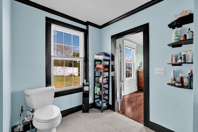 bathroom with crown molding, toilet, baseboards, and tile patterned floors