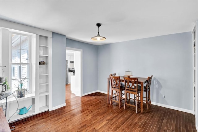 dining room featuring baseboards, built in features, and wood finished floors
