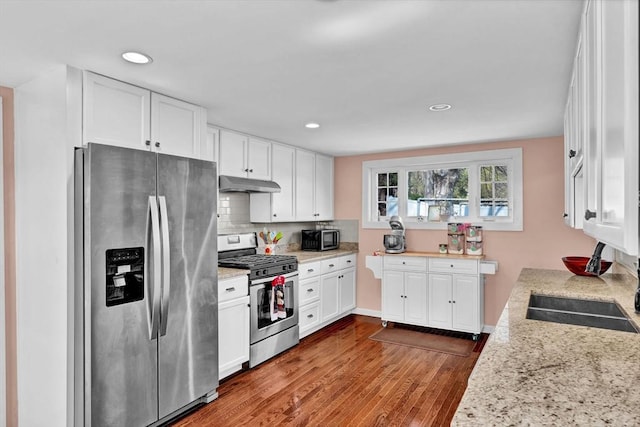 kitchen featuring wood finished floors, stainless steel appliances, white cabinetry, under cabinet range hood, and recessed lighting