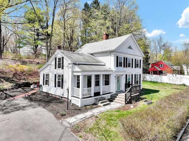 neoclassical home with covered porch, roof with shingles, a chimney, and a front lawn