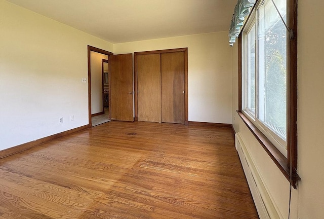 4 Norman Cir, Montague, MA 01376 - unfurnished bedroom with light wood-style floors, baseboards, a closet, and a baseboard radiator