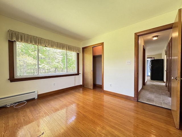 4 Norman Cir, Montague, MA 01376 - unfurnished bedroom with freestanding refrigerator, light wood finished floors, baseboards, a baseboard heating unit, and a closet