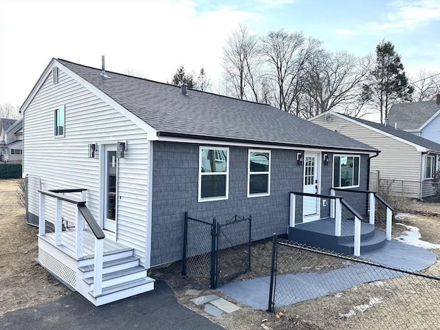 view of front facade featuring fence and roof with shingles