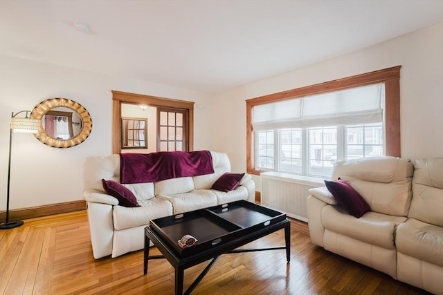 living room featuring wood-type flooring, radiator heating unit, and a healthy amount of sunlight