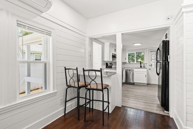 19 Arlington Rd, Dedham, MA 02026 - kitchen featuring stainless steel dishwasher, a wall unit AC, dark wood-type flooring, white cabinetry, and freestanding refrigerator