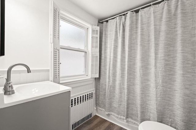 19 Arlington Rd, Dedham, MA 02026 - full bath with radiator heating unit, a wainscoted wall, vanity, wood finished floors, and shower / bath combo