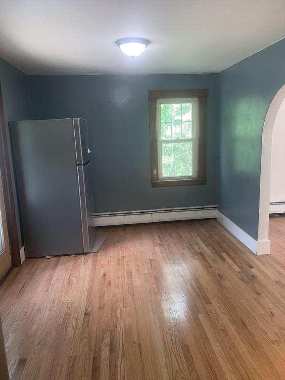 205 Gardner Rd, Hubbardston, MA 01452 - unfurnished room with baseboard heating, arched walkways, wood finished floors, and a baseboard heating unit