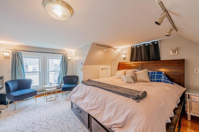 bedroom featuring hardwood / wood-style flooring, vaulted ceiling, and rail lighting