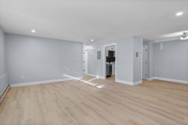 empty room with a textured ceiling, electric panel, light hardwood / wood-style floors, and baseboard heating