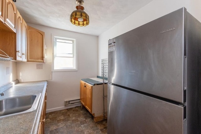 kitchen featuring sink, tasteful backsplash, light brown cabinets, stainless steel refrigerator, and a baseboard heating unit