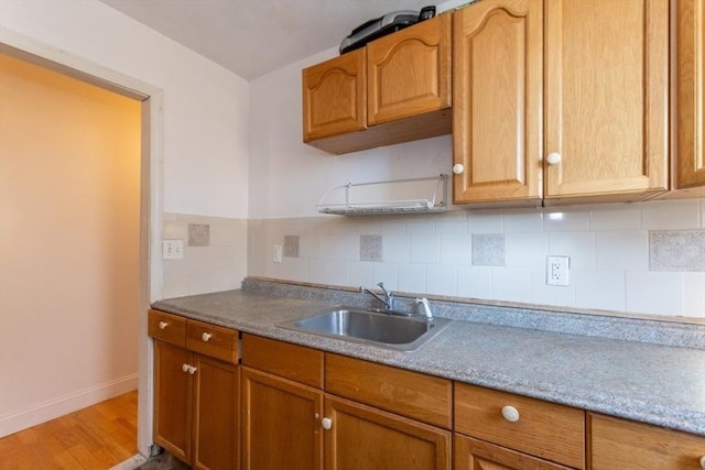 kitchen with sink, light hardwood / wood-style flooring, and backsplash