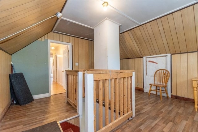 additional living space with hardwood / wood-style flooring, lofted ceiling, and wood walls