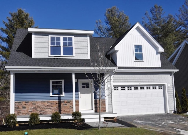 view of front of house featuring driveway, stone siding, an attached garage, and roof with shingles