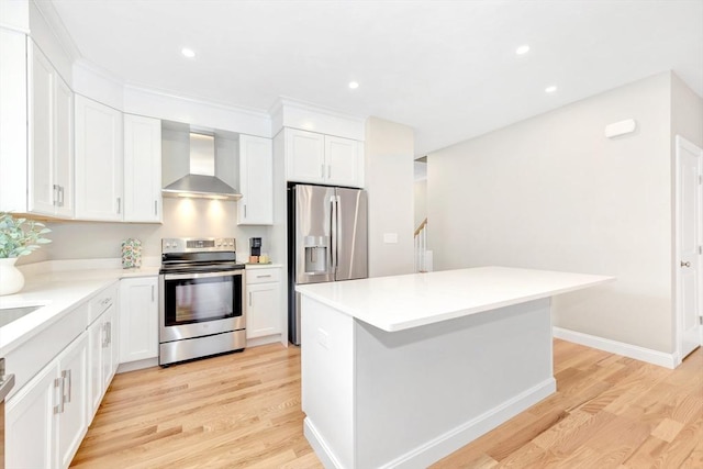 kitchen featuring stainless steel appliances, white cabinetry, and wall chimney range hood