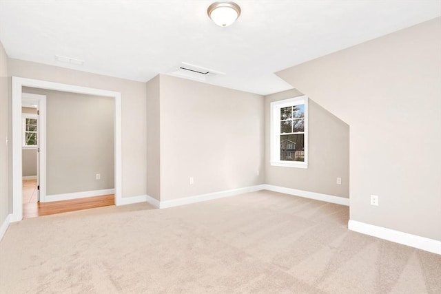 empty room featuring baseboards and light colored carpet