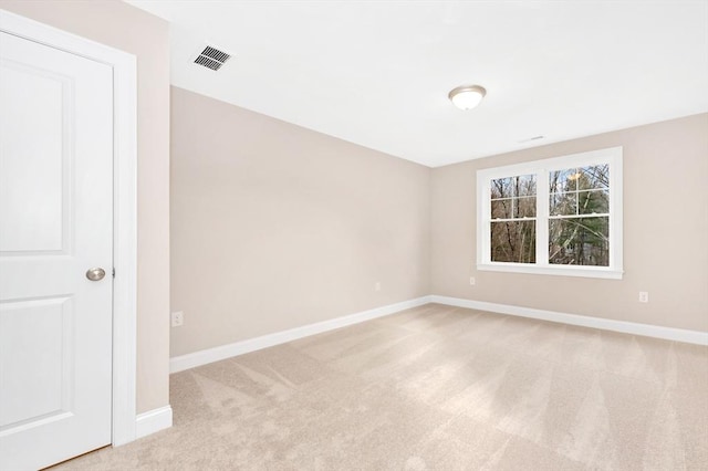 spare room with light colored carpet, visible vents, and baseboards