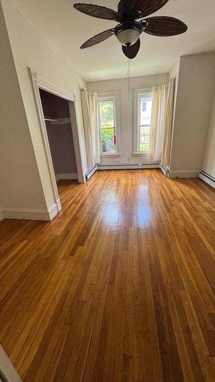 486-488 E Merrimack St, Lowell, MA 01852 - unfurnished bedroom with wood finished floors, baseboards, ceiling fan, a closet, and a baseboard radiator