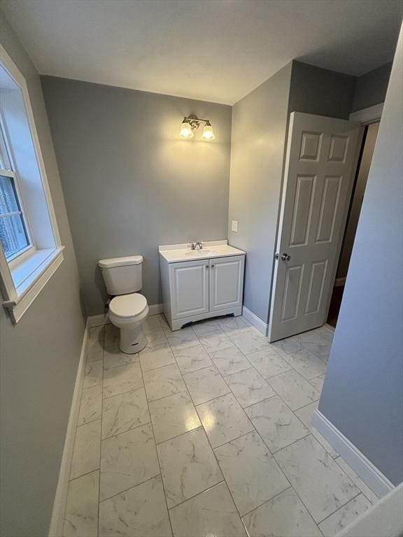 bathroom with toilet, baseboards, marble finish floor, and vanity