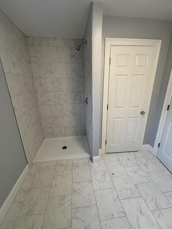 bathroom featuring baseboards, marble finish floor, and a stall shower