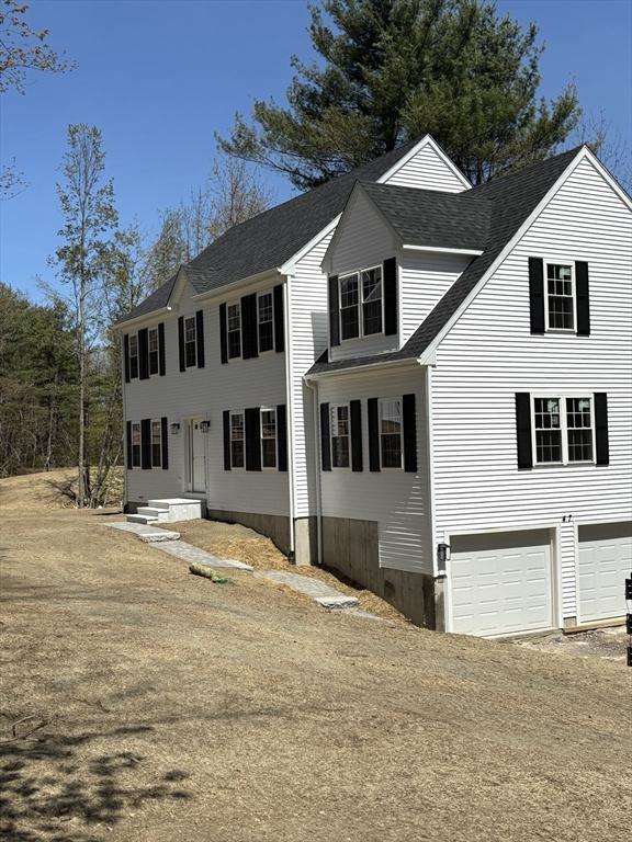 colonial house featuring a garage and roof with shingles