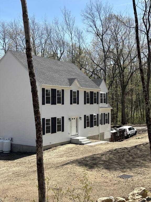colonial house featuring roof with shingles
